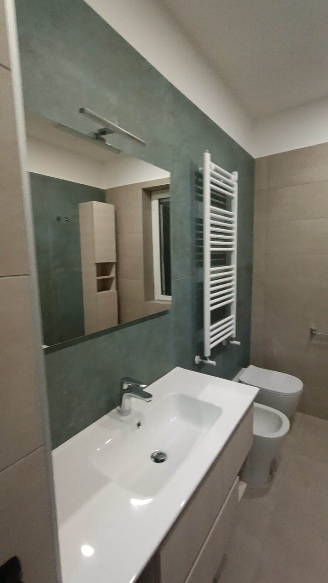 Bagno con parete verde e termoarredo