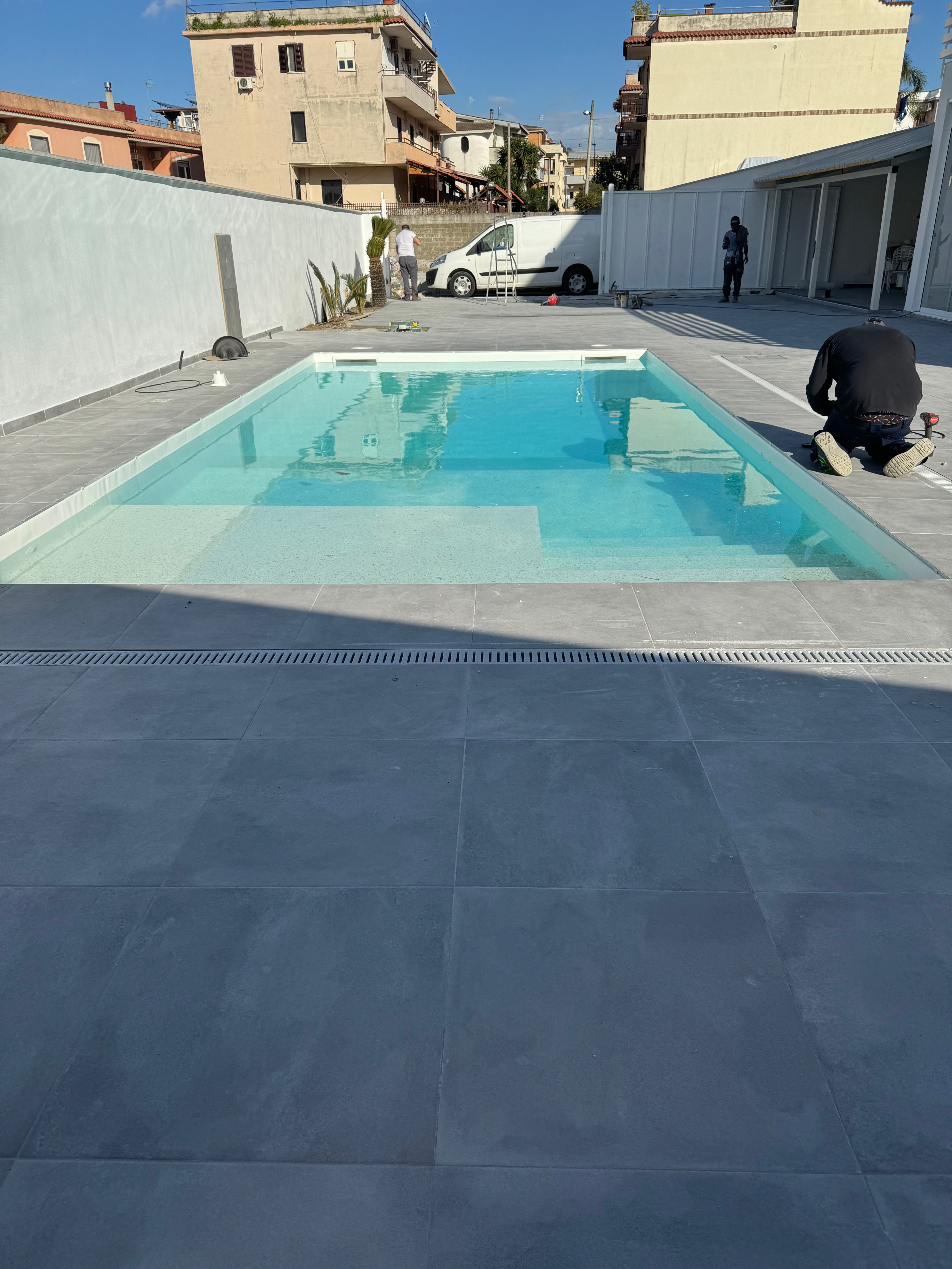 Piscina in fase di completamento con operai al lavoro
