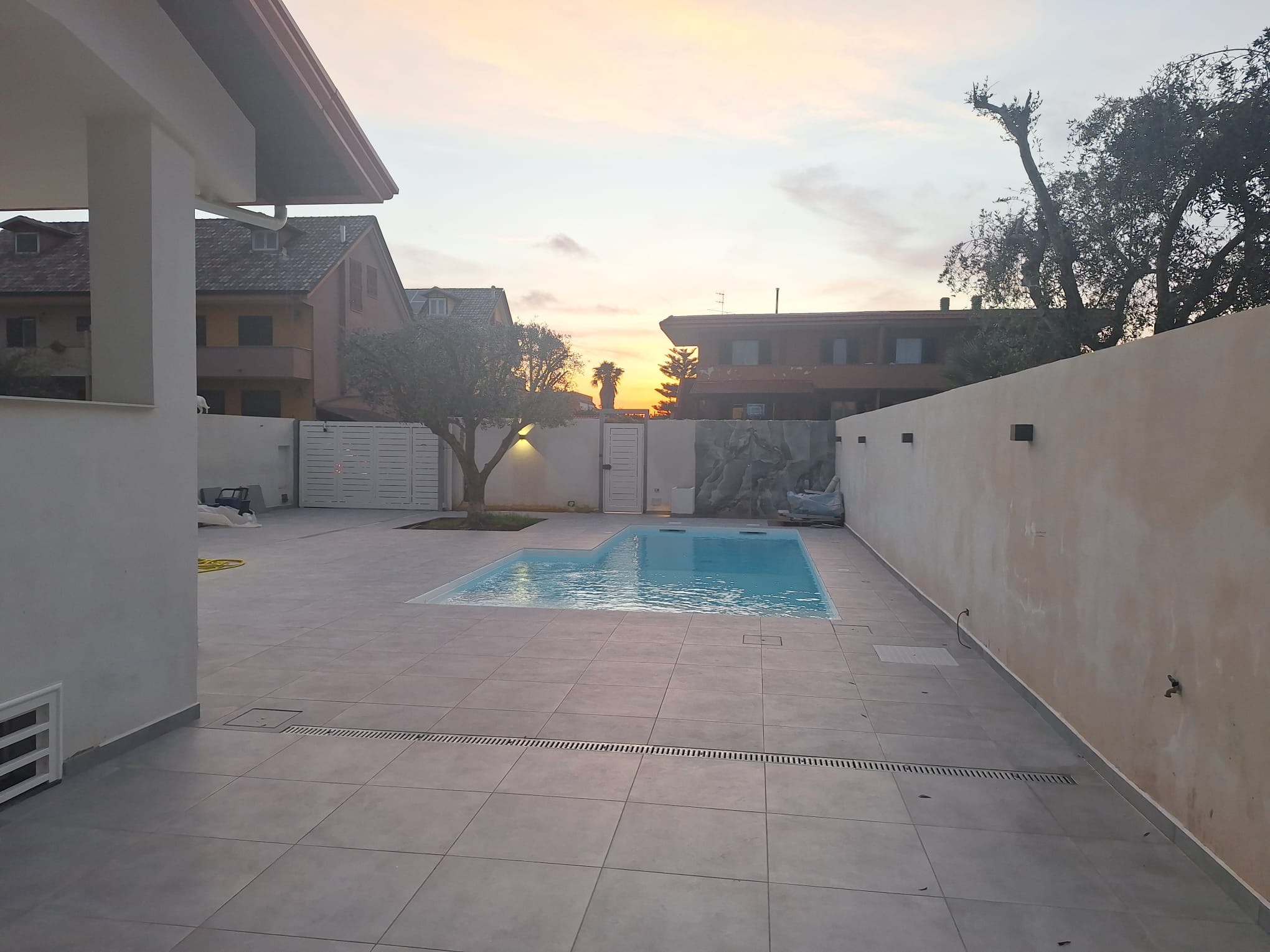 Piscina al tramonto con giardino e olivo