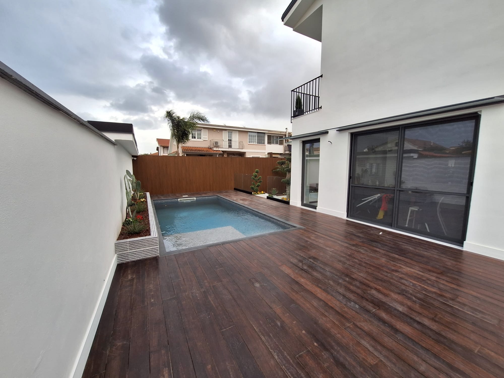 Piscina con solarium in legno e vetrate panoramiche